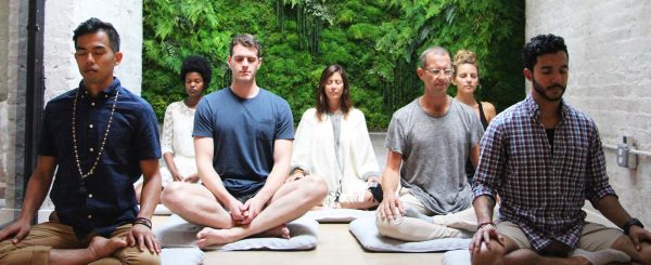 A group of people sitting in the middle of a yoga class.