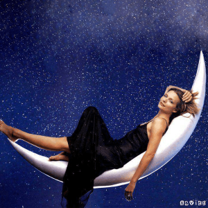 A woman in black dress laying on an inflatable moon.