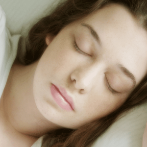 A woman sleeping in bed with her eyes closed.