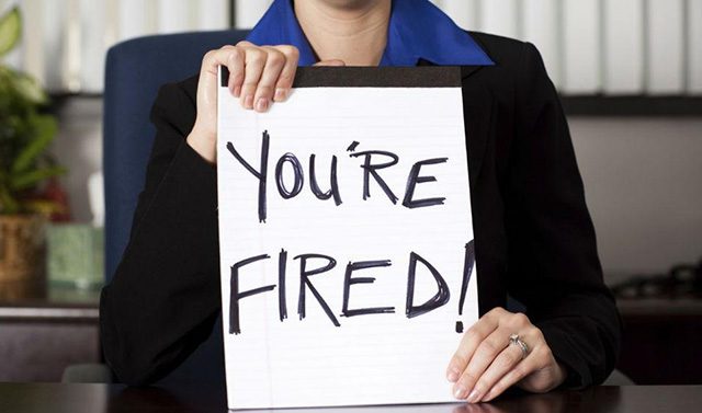A woman holding up a sign that says " you 're fired ".